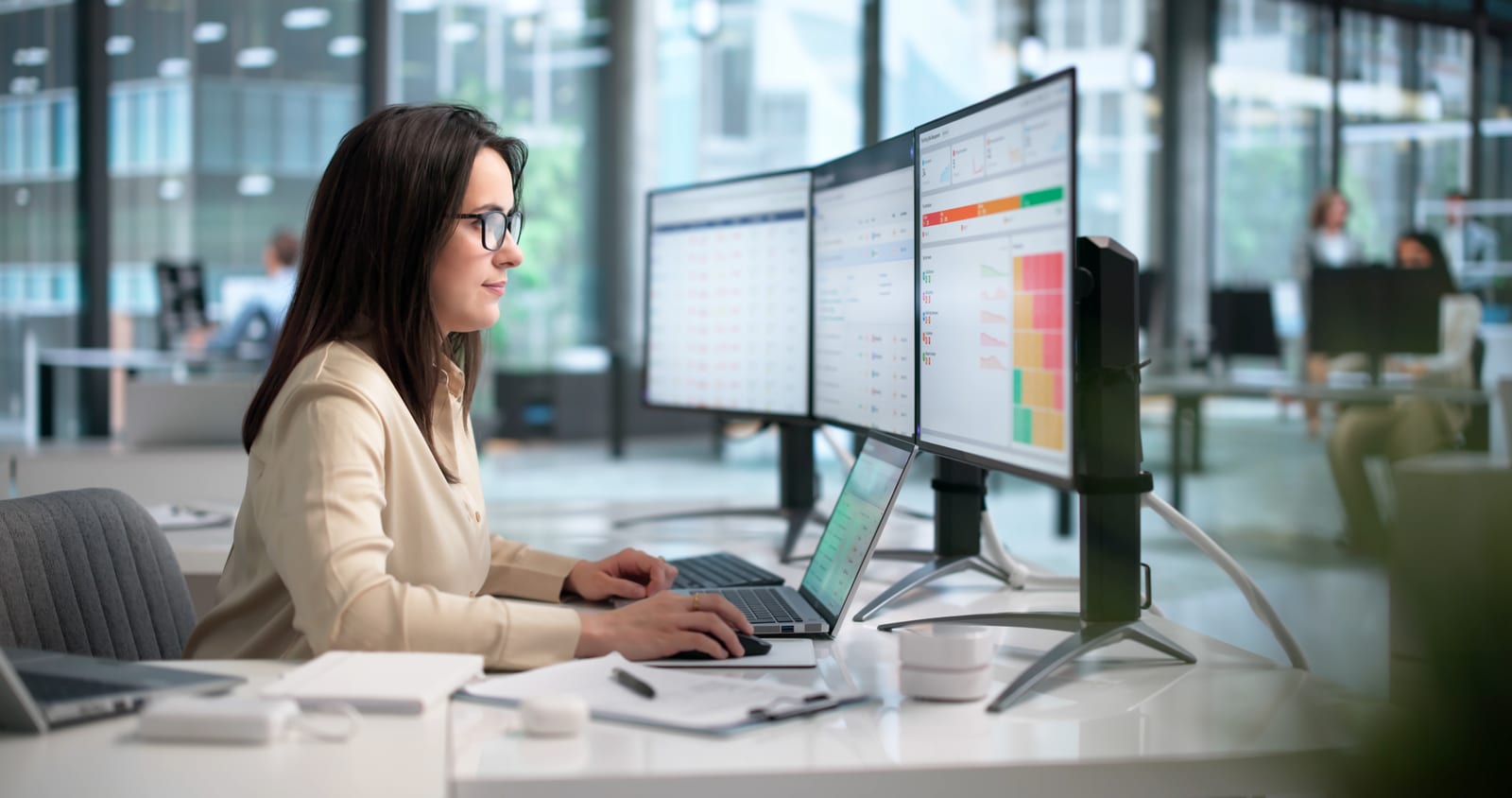 A coordinator reviewing risk and reporting dashboards at her desk
